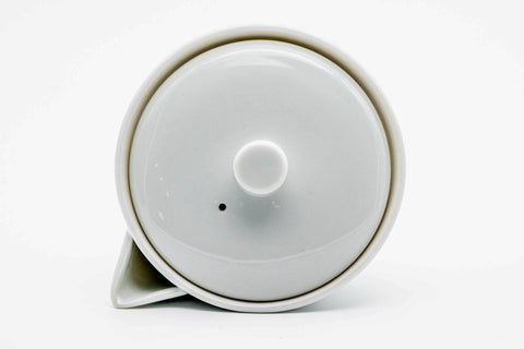 The white houhin with the lid removed and set inverted beside the open mouth.