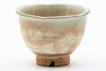 Close-up of one teacup showing the dark beige glaze and pink gohonte spotting.