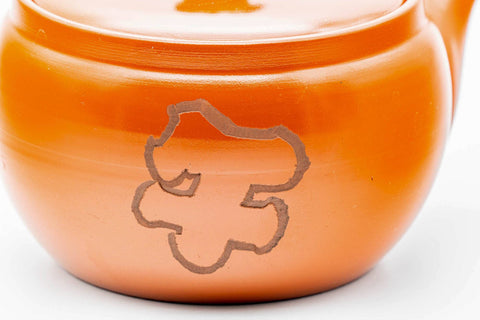 Closeup of the glossy red shudei body of the Tokoname kyusu with an engraved crest motif