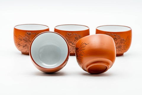 The five teacups, some tipped on their sides, showing the white interiors and bases.