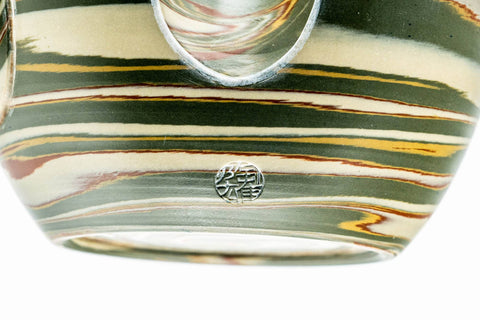 Close-up of the green-and-brown nerikomi marbling and the weathered surface of the clay.