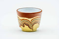 Single red-clay guinomi teacup decorated with a white wave motif near the rim, front view.