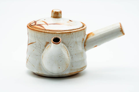 Three-quarter view of the teapot showing the side handle and orange brushed design.