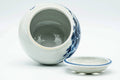 The water bowl with its pierced lid lying flat beside it, showing the open interior.