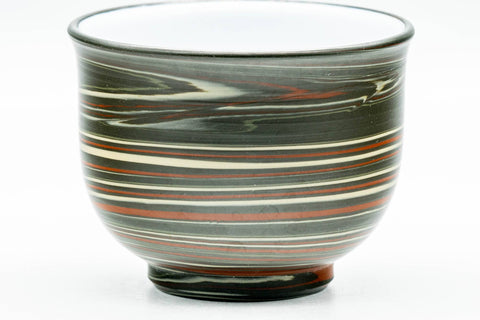 Front view of the nerikomi yunomi emphasizing the layered green, red and yellow pattern and white rim