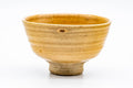 Front view of the yellow Ki-Seto matcha bowl on a white background, its crackled glaze and gently spiralling walls visible.