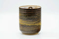 Front view of the lidded brown-beige mizusashi rotated slightly, highlighting the streaked horizontal glaze around the cylindrical body.