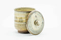 The teacup with its lid leaning against it.