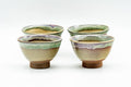 The four drip-glazed guinomi viewed from the front, showing the streaky green-over-beige glaze and exposed clay feet.