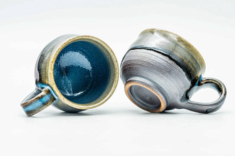 The pair with one cup tipped to show the blue glazed interior and handle.