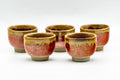 Set of five Agano-yaki guinomi with red-orange bodies and amber drip glaze, grouped together.