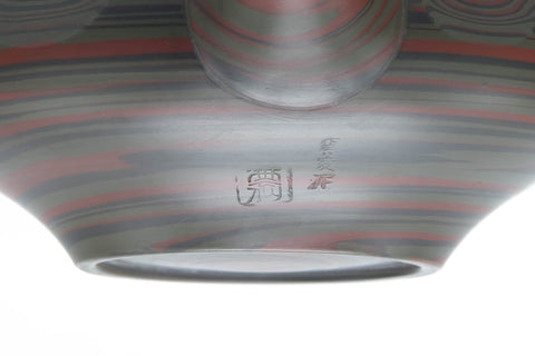 Close-up of the faceted nerikomi surface with reddish marbled bands.