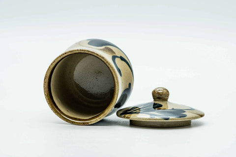 The cup tilted with the lid beside it, showing the glazed interior.