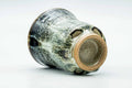 The yunomi resting on its side, showing the unglazed clay foot and base.