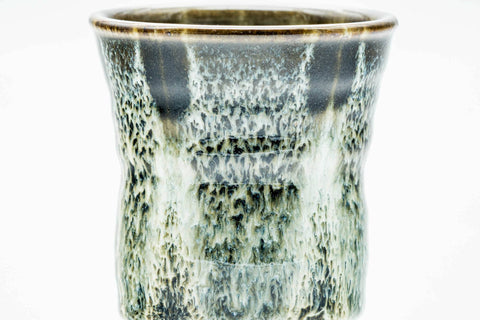 Three-quarter view of the tall yunomi highlighting the drip-glaze texture and pale rim.
