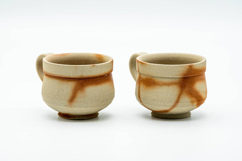 Three-quarter view of the pair of teacups, highlighting the hidasuki marks and handles.