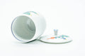 The cup tipped with the lid removed, revealing the white interior and blue rim line.
