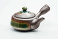 Banko-yaki side-handle kyusu in grey clay with a green ash-glaze band, lid on, shown from the side.