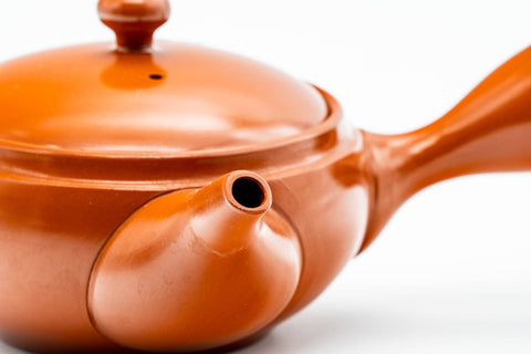 Close-up angled view of the spout and rounded red shudei body with the lid on.
