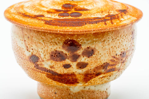 Close-up of the cup body showing the orange Shino glaze and reddish floral motif.