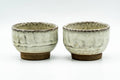 The pair of yunomi viewed at a slight angle, showing their glazed interiors.