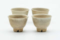 The four Hagi-yaki teacups grouped together, showing their weathered beige glaze.