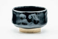 Jet-black chawan, front view showing the glossy glaze and a brushed motif