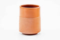 Side view of the teacup, showing the brick-red clay and textured lower body.