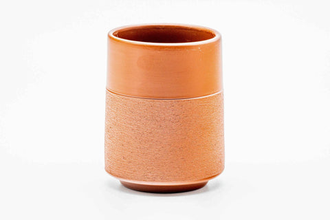 Side view of the teacup, showing the brick-red clay and textured lower body.