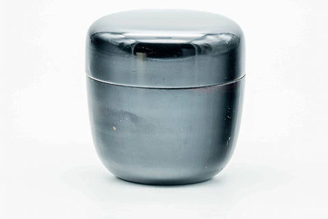 Small black-urushi ko-natsume matcha caddy, lid on, side view of the glossy domed lid