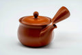 Front view of the round red kyusu showing the spout, lid on.