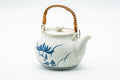 Japanese Dobin - Blue Floral White Textured Arita-yaki Porcelain Teapot - 500ml - front three-quarter view with overhead rattan-wrapped bail handle and blue floral decoration