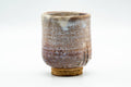 Front view of an earthy white-glazed Hagi-yaki yunomi, a tall cylindrical teacup with a toasted unglazed foot