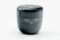 Black-lacquer matcha tea caddy, lid on, front view of the gold soaring-bird and wave maki-e