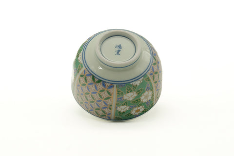 The yunomi tilted to show its foot ring and underside with the patterned exterior