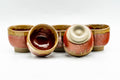 The set with two cups tipped to reveal the glazed interior and unglazed foot.