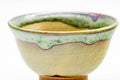 Close-up of a single guinomi's rim and interior, highlighting the green drip glaze pooling over the beige body.