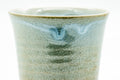 Close-up of the cup's body showing the pale Hagi glaze, faint throwing lines and the blue drip.
