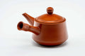 Side view of the red kyusu with handle and spout, lid on.