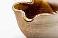 Close three-quarter view of the wavy rim and amber interior glaze.
