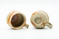 Angled top view into the two cups, revealing their unglazed interiors and handles.