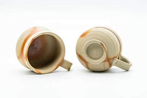 Angled top view into the two cups, revealing their unglazed interiors and handles.