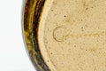 Underside of the mizusashi showing the unglazed foot and an incised maker's mark on the base.