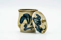 Angled view of the lidded cup highlighting the painted floral brushwork on the body.