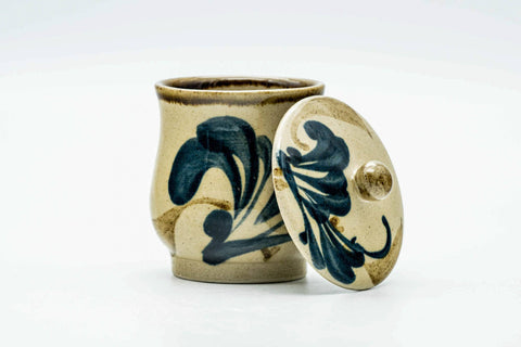 Angled view of the lidded cup highlighting the painted floral brushwork on the body.