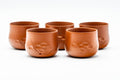 The five red yunomi cups in a row, each with engraved floral detailing.