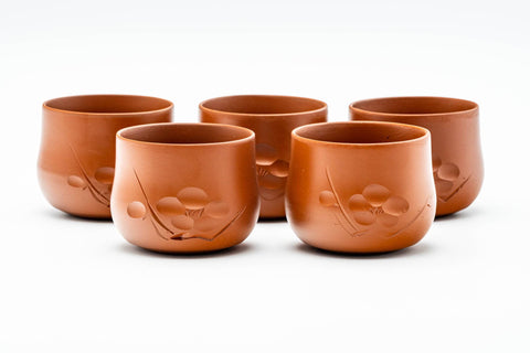 The five red yunomi cups in a row, each with engraved floral detailing.