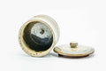 The teacup with the lid removed, showing the dark glazed interior, lid beside it.