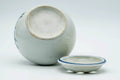 Angled view showing the white glazed interior of the bowl with the pierced lid set to the side.