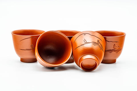 The katakuchi resting on its side beside the five guinomi cups, showing the set together.